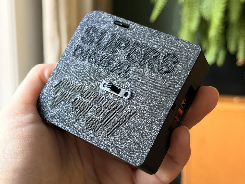 The cartridge held in one hand, lid up: the engraved SUPER8 DIGITAL title, the small slide switch and the FABI logo.